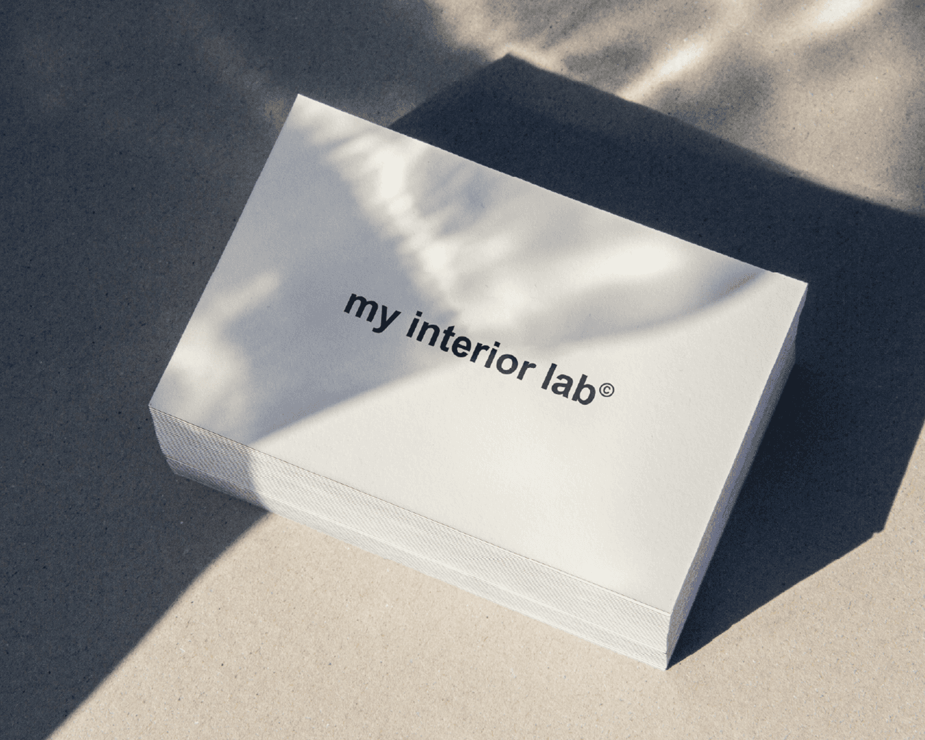 Business cards for MY INTERIOR LAB on polished concrete floor, black text on light background, minimalist and contemporary look, visual identity and design by Studio La Folie.