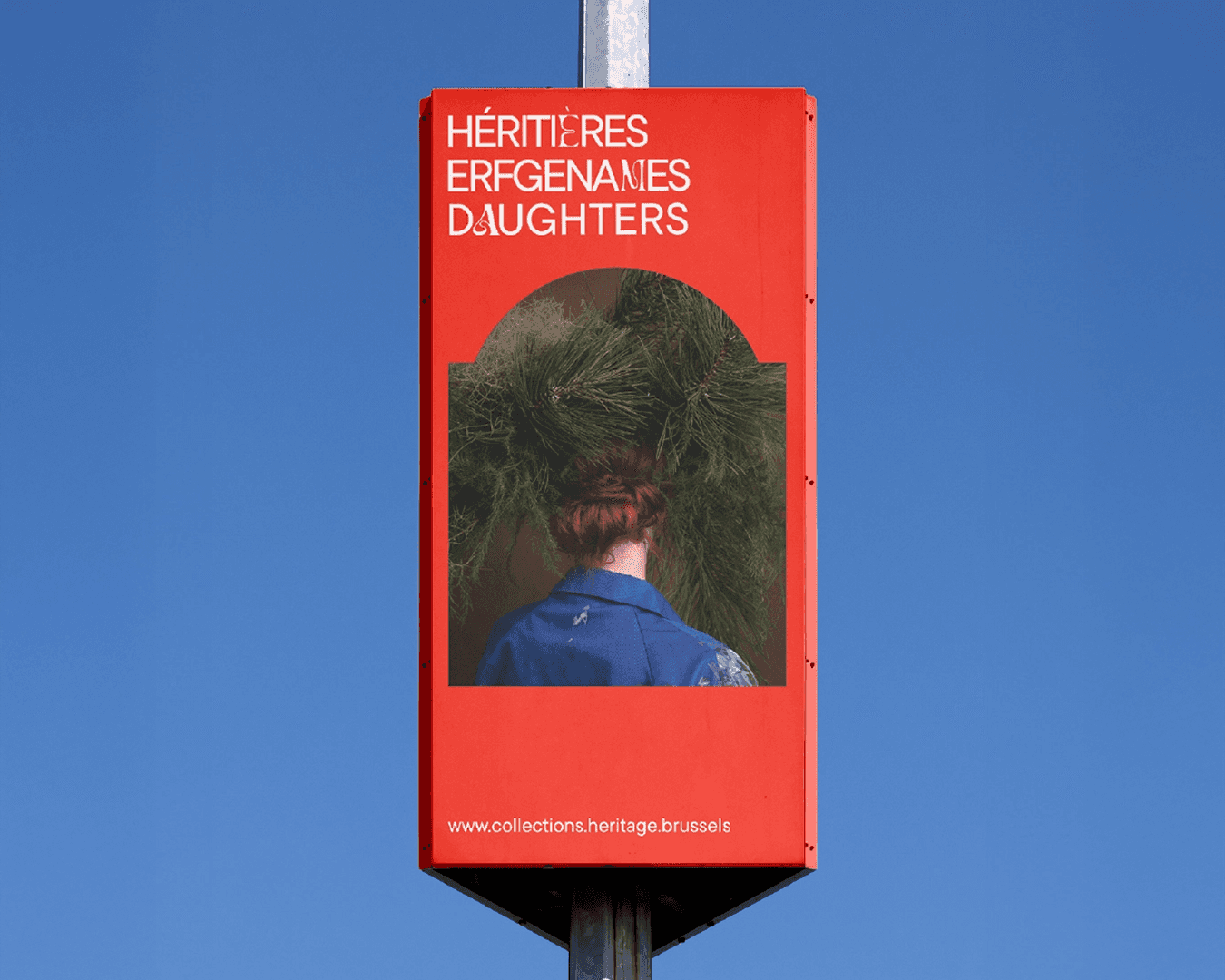 Poster of the Héritières photography exhibition in Brussels, wrapped around an urban light pole, featuring the artist’s portrait in the foreground and the trilingual Héritières logo inside an Art Nouveau-style frame; branding designed by Studio La Folie.